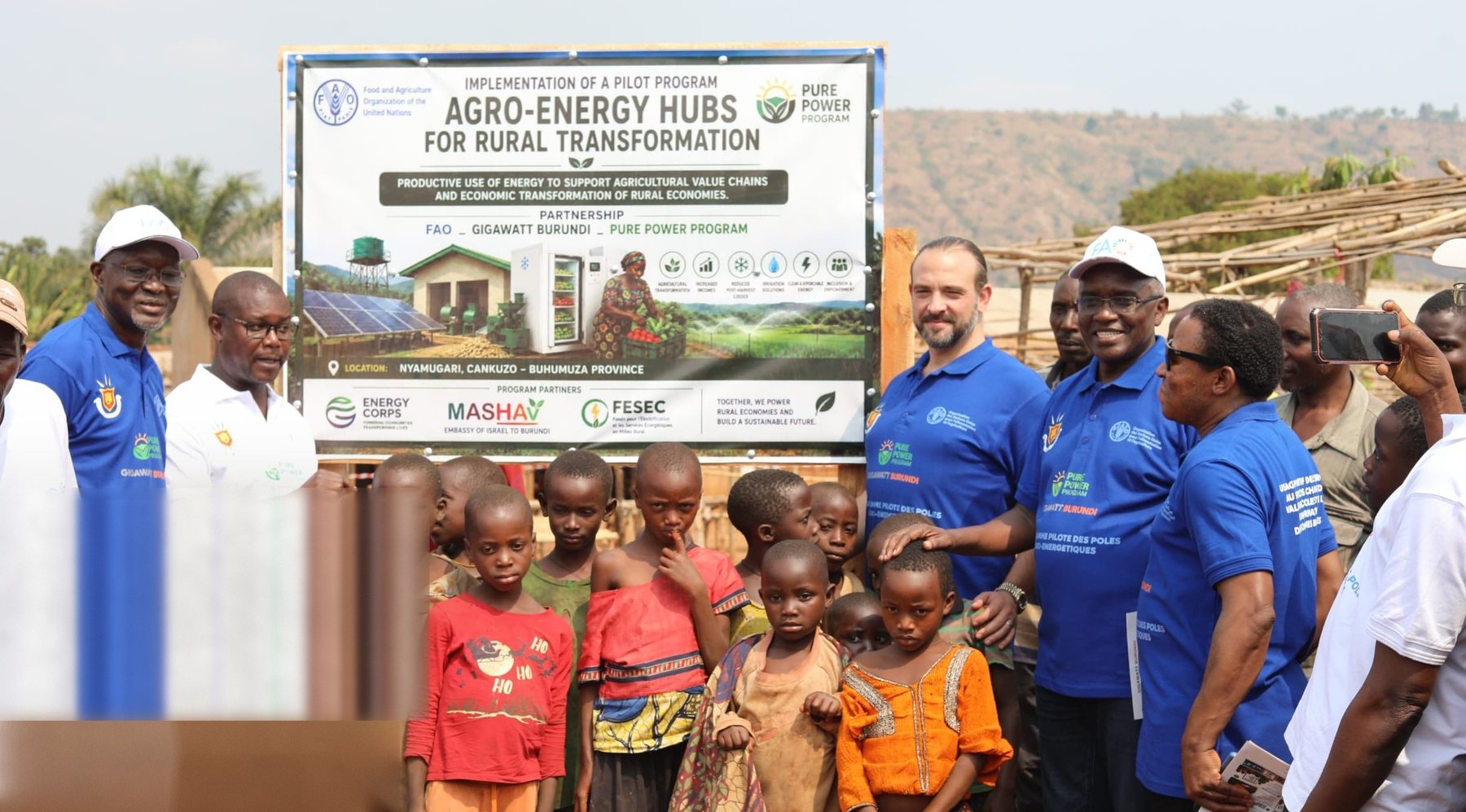 Officials, the FAO Representative in Burundi and community members gathered at the project banner for the groundbreaking of the Nyamugari agro-energy hub.